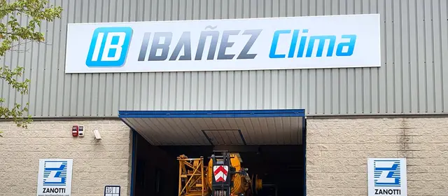 Fachada de la nave de IBAÑEZ CLIMA en Lleida con el rótulo de la empresa y un camión grúa entrando al taller.