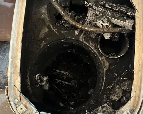 Cuerpo de un filtro de partículas abierto por corte, con la cerámica quemada y desmenuzada en trozos negros dentro de la carcasa.