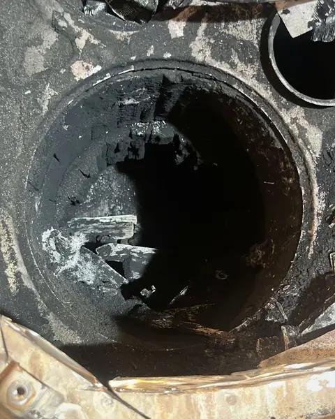 Interior de la carcasa de un filtro de partículas abierto, con la cerámica desmenuzada y restos negros dentro.