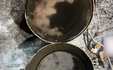 Dos mitades de un filtro de partículas abierto, con las caras de la cerámica manchadas de hollín.
