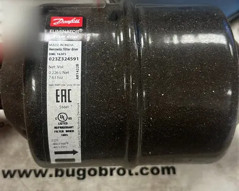 Filtro deshidratador con la etiqueta del fabricante, sobre una mesa.
