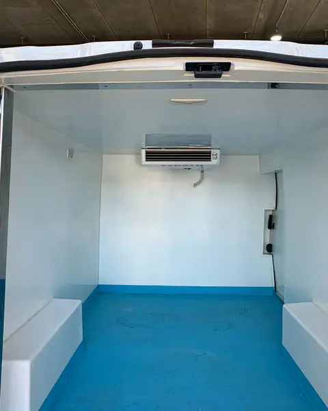 Caja isoterma de una furgoneta abierta por detrás, con el evaporador Zanotti arriba en la pared del fondo y el suelo azul.
