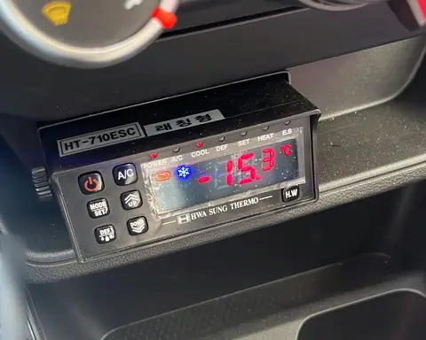 Mando de cabina de un equipo de frío Hwasung Thermo, encendido, bajo los mandos de la climatización del vehículo.