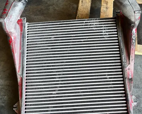 Intercooler de gran tamaño, con sus dos tomas, sobre el suelo del taller.