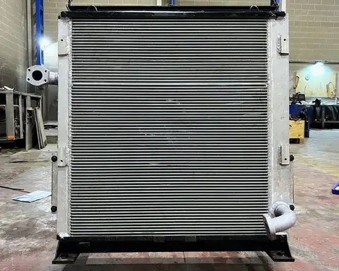 Radiador de aluminio de gran tamaño, con bastidor y bocas de conexión, colgado de cadenas en la nave.