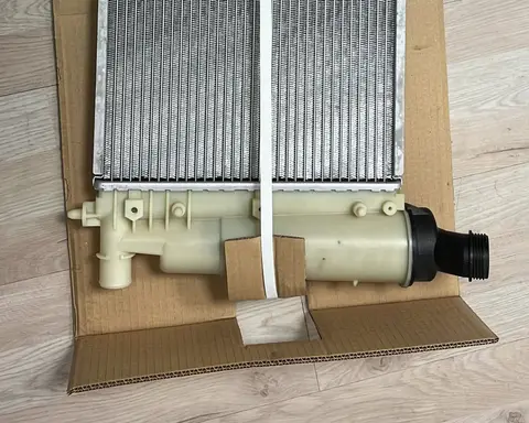 Depósito de plástico de un radiador de aluminio nuevo, sobre su caja de cartón.
