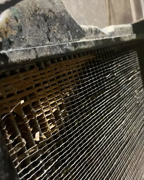 Detalle del panal de cobre de un radiador, con las aletas corroídas y deshechas en una zona junto al depósito.