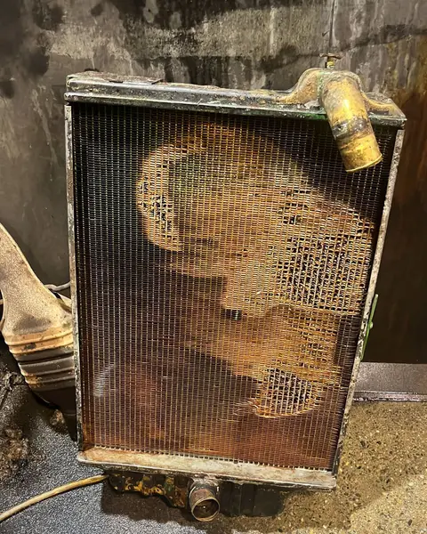 Radiador de cobre de pie en el taller, con el panal corroído y deshecho por zonas.